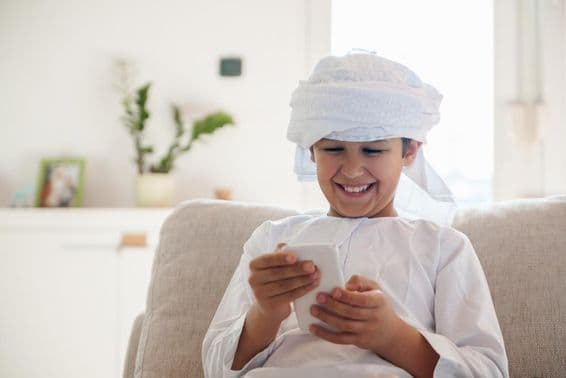 گھر میں اسمارٹ فون استعمال کرتا ہوا عرب بچہ۔