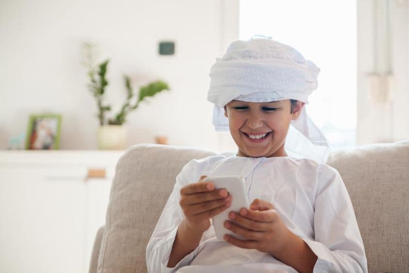 گھر میں اسمارٹ فون استعمال کرتا ہوا عرب بچہ۔