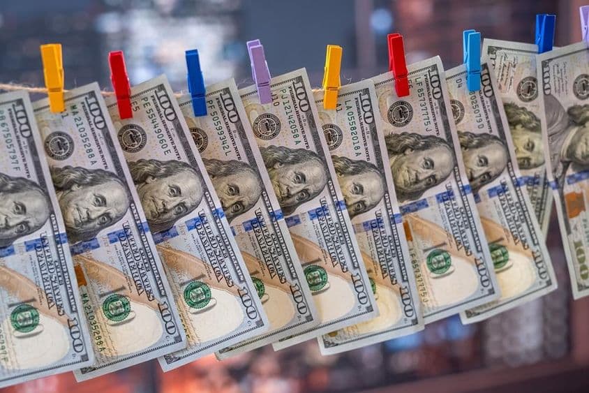 لکڑی کے کلپ کے ساتھ کپڑے کی لائن پر لٹکا ہوا ۱۰۰ امریکی ڈالر کا بل۔