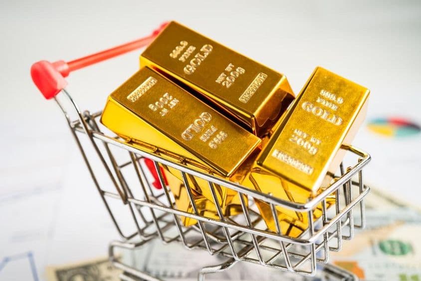 سونے کا بسکٹ امریکی ڈالر کے نوٹوں پر شاپنگ کارٹ میں۔
