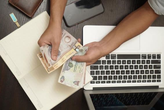 ایک آدمی متحدہ عرب امارات کے درہم کے نوٹوں کو گنتے ہوئے