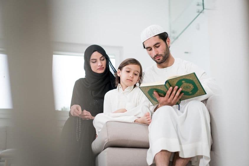 نوجوان والدین اور ایک چھوٹا لڑکا ایک کتاب سے پڑھ رہے ہیں۔