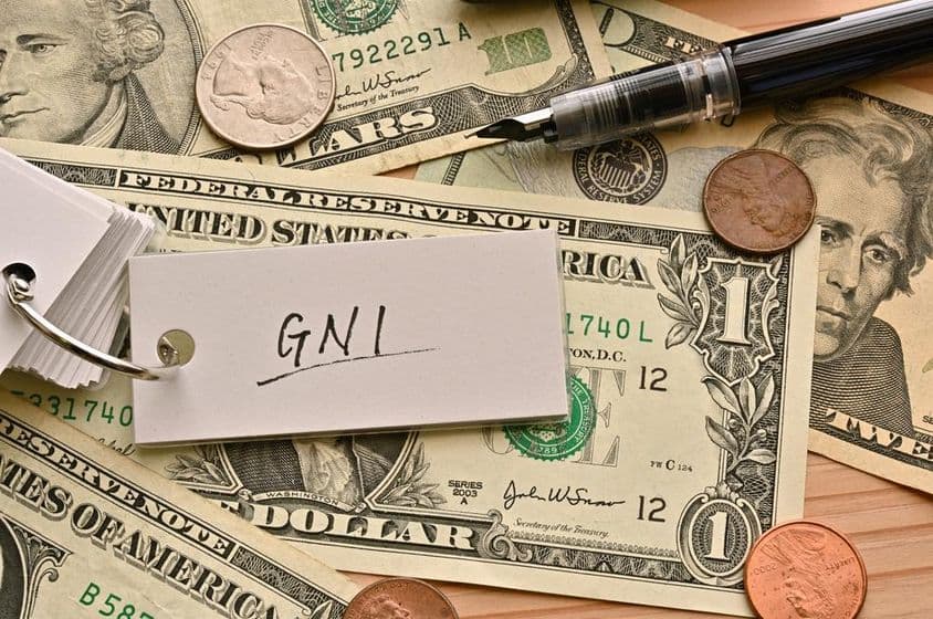 مالیاتی اصطلاح جی این آئی ڈالر کے نوٹوں کے اوپر لکھی ہوئی ایک میز پر۔