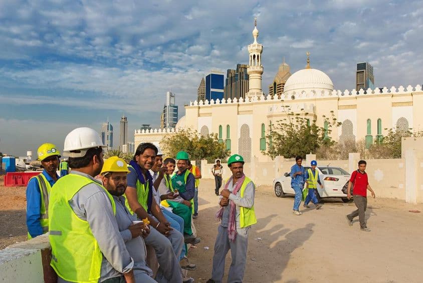 جدید دبئی کے مرکز میں ایک مسجد کے قریب آرام کرتے ہوئے تعمیراتی کارکن۔