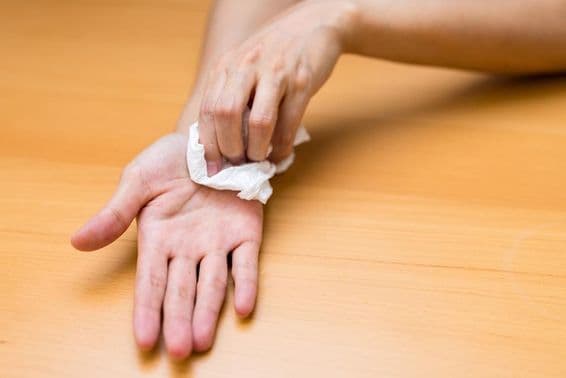 عورت پسینے سے بھرے ہاتھوں سے پریشان۔