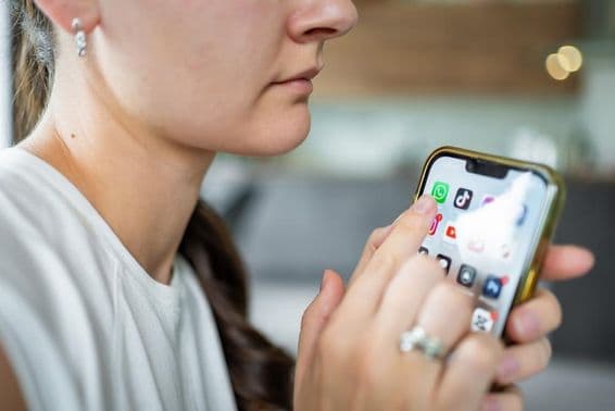 ایک عورت جس کے آئی فون کی سکرین پر واٹس ایپ چیٹ ایپلیکیشن نظر آ رہی ہے۔