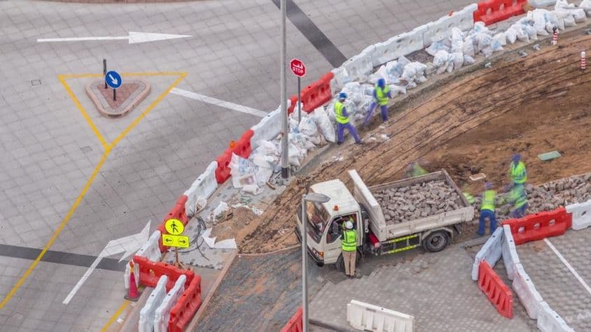 فٹ پاتھ کی مرمت کا عمل، کئی تعمیراتی کارکن اور سامان فٹ پاتھ اور کنکریٹ کو توڑ رہا ہے۔