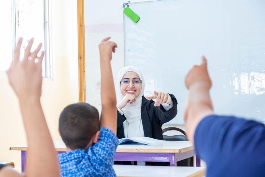 طلباء اٹھے ہوئے ہاتھوں کے ساتھ، حاضر اور استاد کو جواب دیتے ہوئے۔