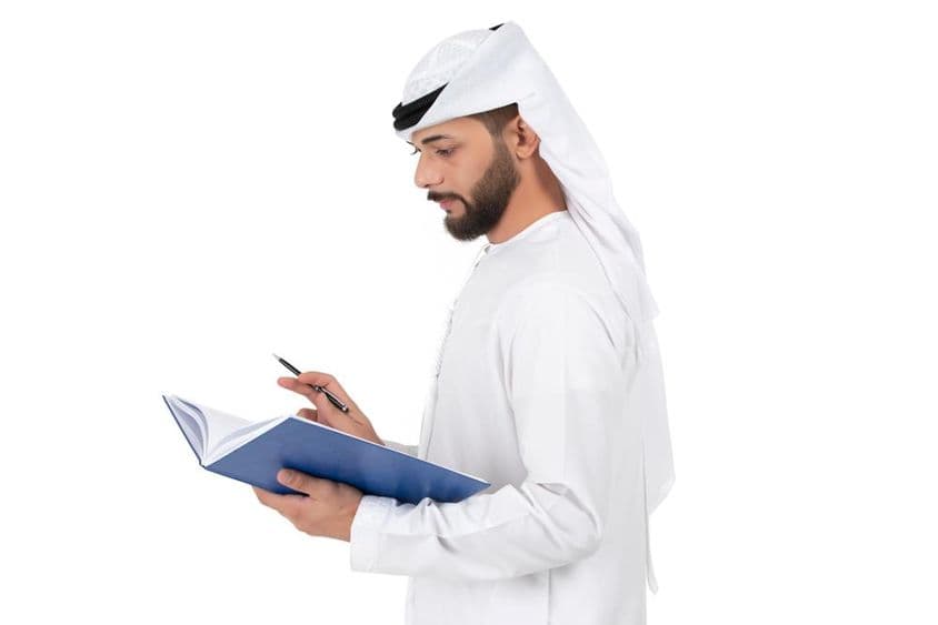 ایک جوان عرب استاد کتاب میں لکھتے ہوئے۔