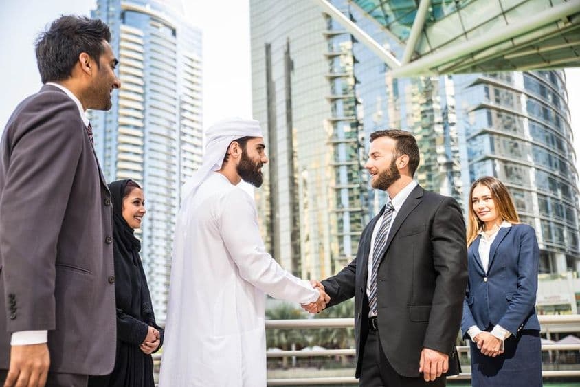 دبئی میں بیرونی ملاقات کرتے ہوئے مختلف قومیتوں کے کاروباری افراد کا گروپ۔