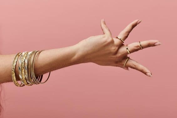 ایک بھارتی عورت اپنی کلائی پر سونے کی چوڑیاں پہنے ہوئے باذوق انداز میں کھڑی ہے۔