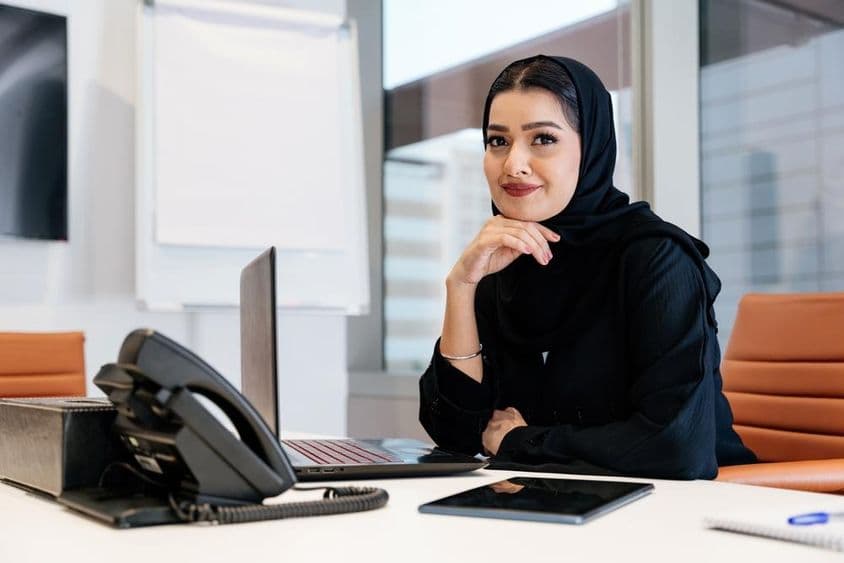 مشرقی وسطیٰ کی کاروباری خاتون جو عربی روایت کے مطابق عبا پہن کر دفتر میں بیٹھی ہے۔