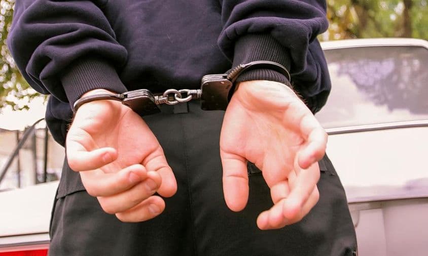 ایک شخص، جس کے ہاتھ پیچھے کف لگی ہوئی ہیں۔