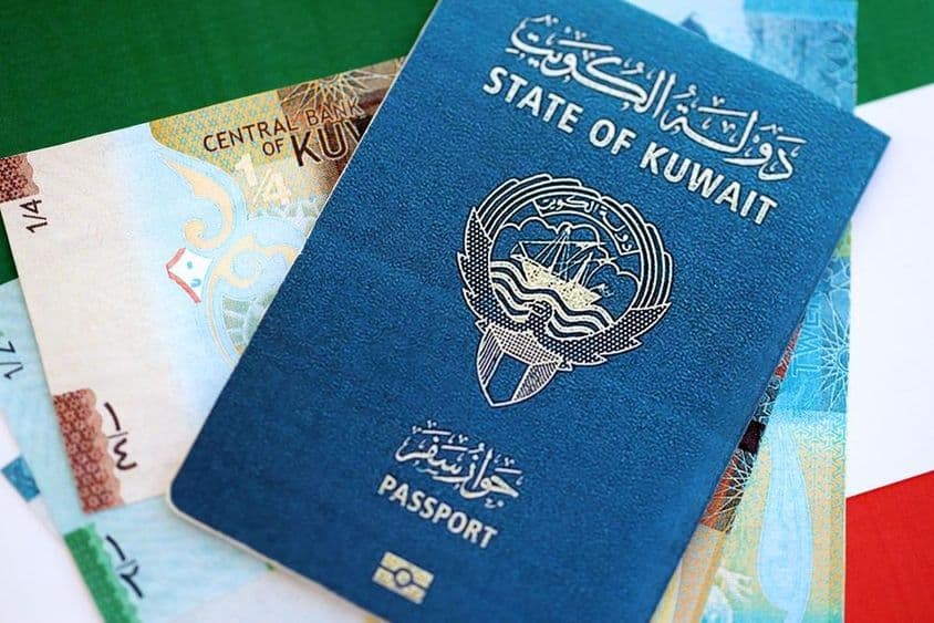 کویتی دینار اور پاسپورٹ میز پر رکھے ہوئے ہیں۔