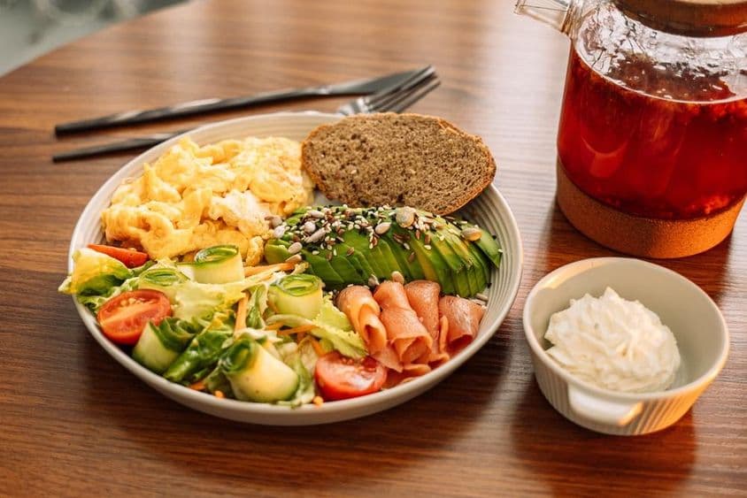 انڈے، اواکاڈو، سبزیاں، سلاد اور رسبری چائے کے ساتھ صحت مند ناشتہ۔