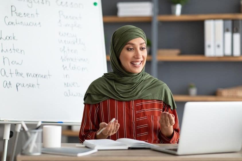 مسرت بھری خاتون عرب معلم اسکارف میں ویڈیو کال کا آغاز کر رہی ہیں۔