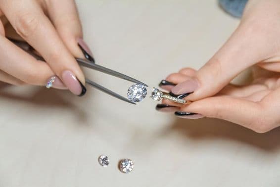 ایک زیور سازی کرنے والی خاتون کے ہاتھ ہیرے کو پکڑے ہوئے ہیں۔