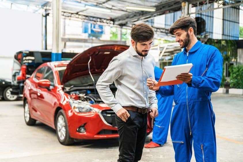مکینک کار کے معائنے کی چیک لسٹ کلائنٹ کو دکھا رہا ہے۔