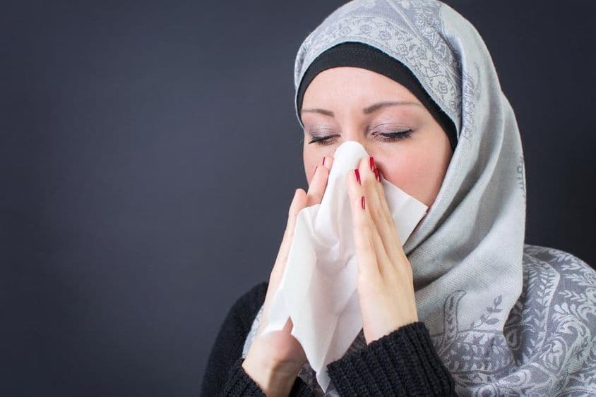 زکام اور بہتی ناک کے ساتھ ایک خوبصورت مسلم خاتون۔