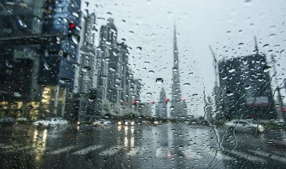 دبئی میں بارش کے دوران پس منظر میں بلند عمارات۔