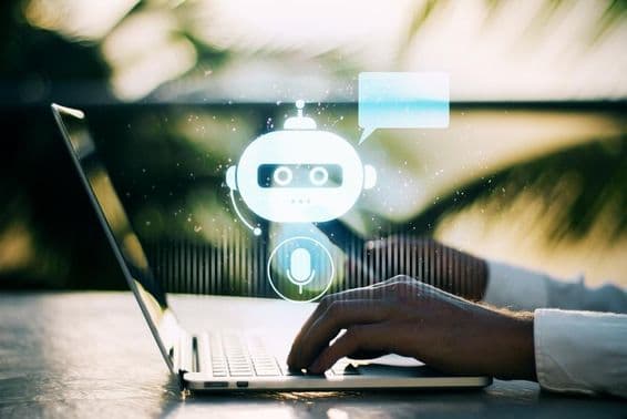 ایک شخص لیپ ٹاپ پر ٹائپ کر رہا ہے جس کے بیرونی منظر میں چیٹ بوٹ آئیکن دھندلا ہے۔