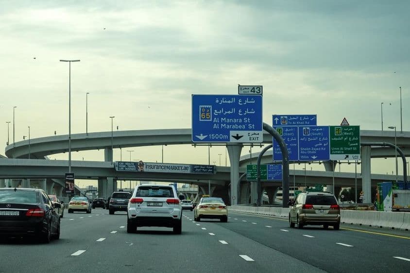 دبئی کی سڑک گاڑیوں اور اوور پاس کے اشتہار کے ساتھ۔