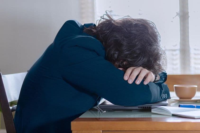 پیر کے دن دفتر میں لیپ ٹاپ پر آرام کرتا ہوا شخص۔