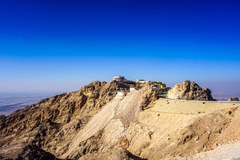العین جبل حفیت پہاڑی منظرکش منظر جس میں چوٹیاں اور عمارتیں شامل ہیں۔