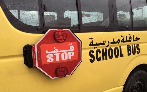 ایک خالی سکول بس جس کے سائیڈ میں سرخ سٹاپ کا انتباہی نشان ہے جو سڑک کنارے رکھی گئی ہے۔