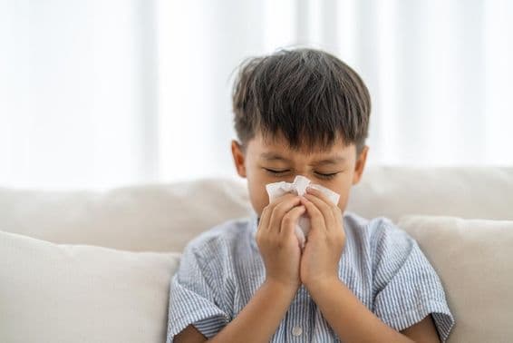 ایک نوجوان ایشیائی لڑکا چھینک رہا ہے۔
