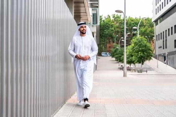 عربی مسلمان کاروباری شخص شہر کے کاروباری علاقے میں چل رہا ہے۔