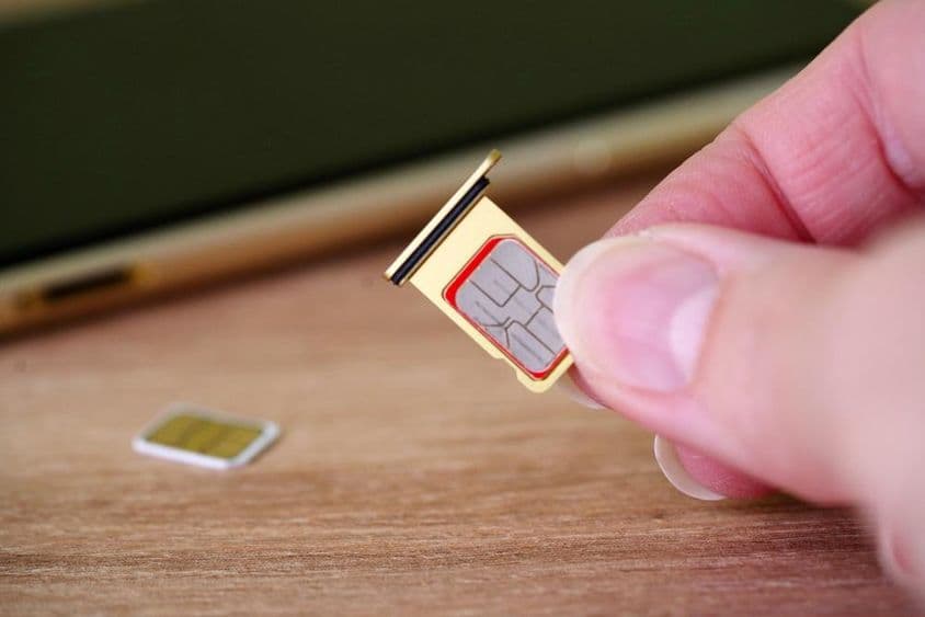 شخص جو موبائل فون کے پیچھے سم کارڈ لگا رہا ہے۔