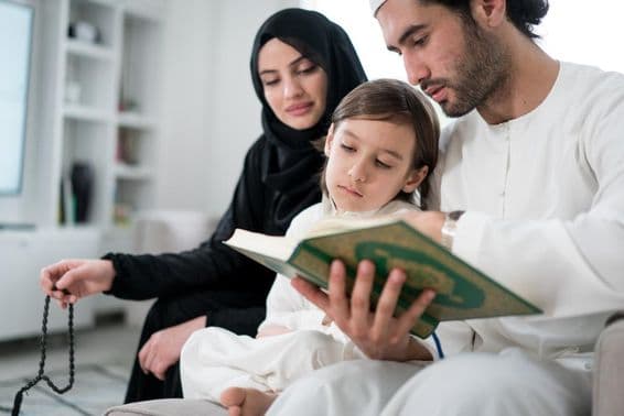 رمضان کے دوران والدین اپنے بیٹے کو قرآن پڑھاتے ہوئے