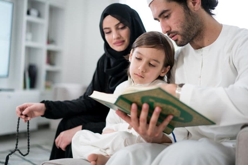 رمضان کے دوران والدین اپنے بیٹے کو قرآن پڑھاتے ہوئے