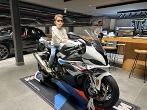 چشمہ پہنے لڑکا BMW موٹر سائیکل پر بیٹھا ہوا۔