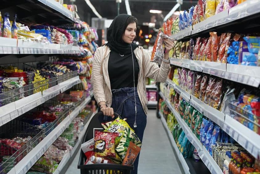 ایک نوجوان عرب خاتون سپر مارکیٹ میں ناشتے کو دیکھ رہی ہے۔