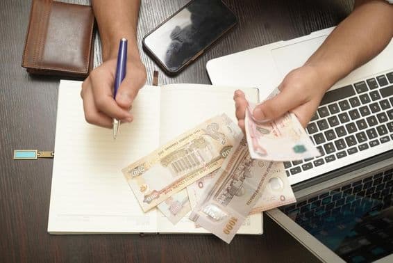 ایک شخص متحدہ عرب امارات کے درہم کی گڈیاں گنتے ہوئے