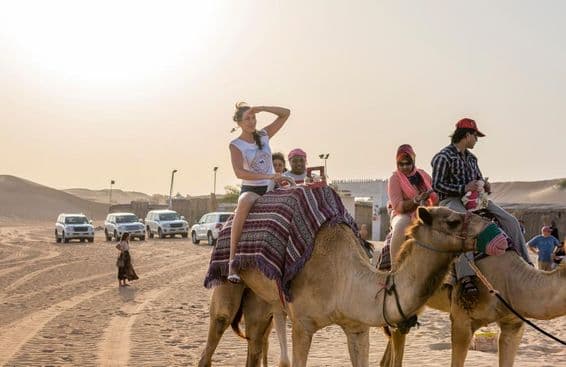 دبئی کے صحرا میں سیاح اونٹ سواری کرتے ہوئے
