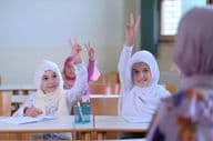 مسلمان طلباء اساتذہ کے سوالات کے جواب دینے کے لیے ہاتھ اٹھائے ہوئے ہیں۔