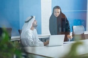 دبئی کے ایک کاروباری دفتر میں روایتی لباس میں ایک مرد اور عورت کام کر رہے ہیں۔