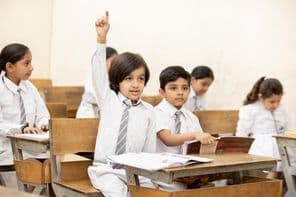 ہاتھ اٹھائے ہوئے خوشحال بھارتی سکول کا بچہ