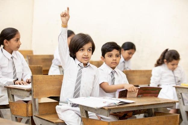 ہاتھ اٹھائے ہوئے خوشحال بھارتی سکول کا بچہ